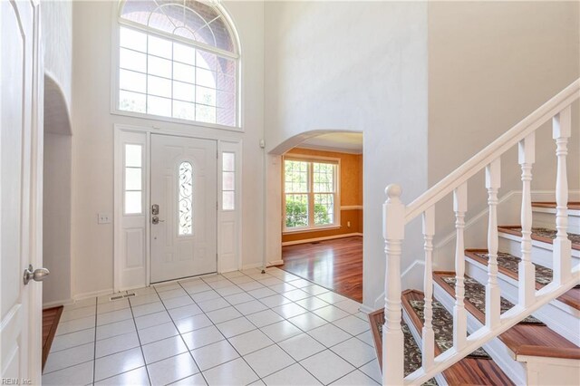 tiled foyer entrance with a towering ceiling, arched walkways, and stairway
