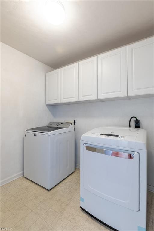 washroom with cabinet space, separate washer and dryer, light flooring, and baseboards