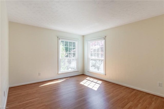 unfurnished room featuring wood finished floors, baseboards, and a textured ceiling