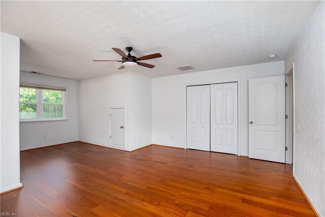 unfurnished bedroom with wood finished floors, a closet, ceiling fan, and baseboards