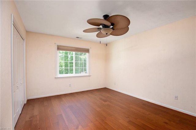 unfurnished bedroom with wood finished floors, baseboards, a closet, and a ceiling fan