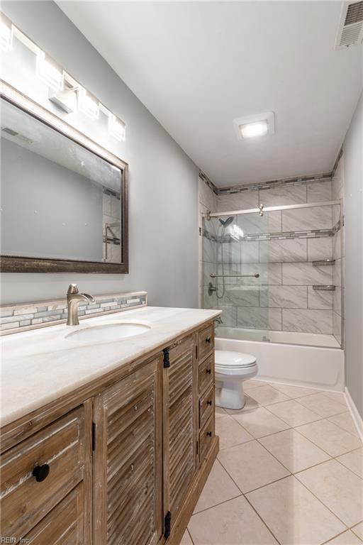full bathroom featuring tile patterned floors, toilet, vanity, and bath / shower combo with glass door