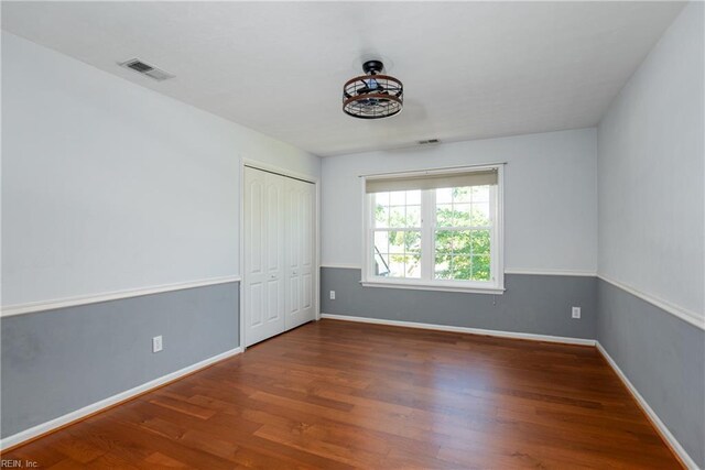 unfurnished bedroom featuring wood finished floors, baseboards, and a closet