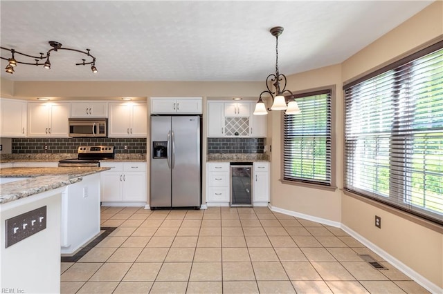 kitchen with appliances with stainless steel finishes, wine cooler, tasteful backsplash, white cabinetry, and a chandelier