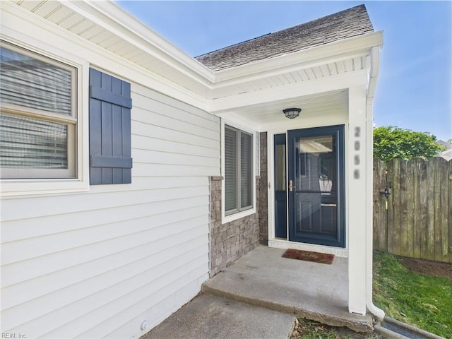 entrance to property featuring fence and roof with shingles