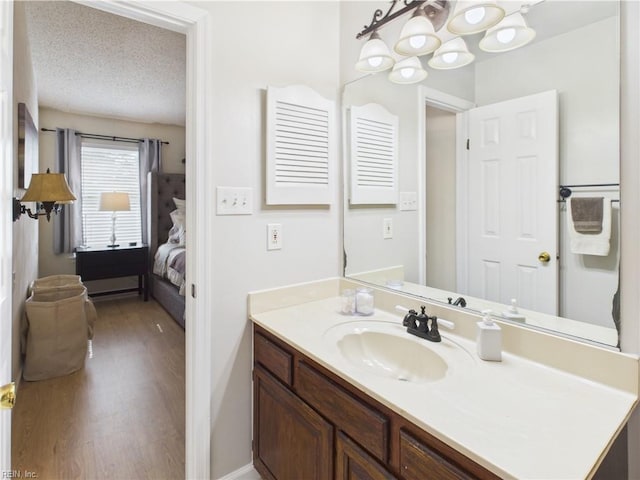 ensuite bathroom featuring wood finished floors, vanity, and a chandelier