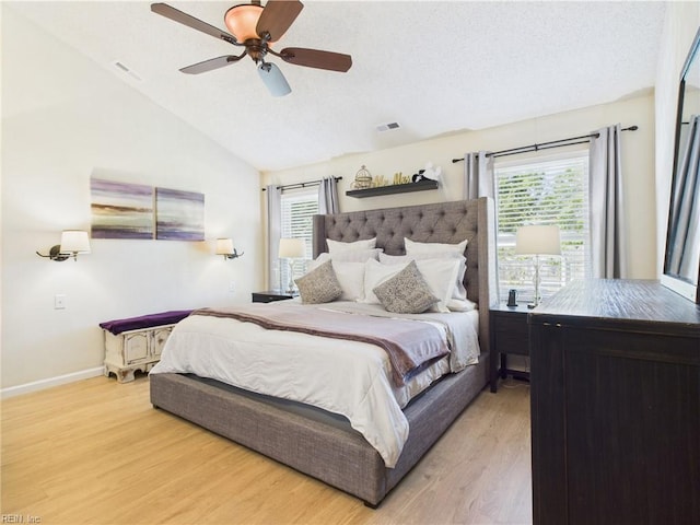 bedroom with light wood-type flooring, lofted ceiling, baseboards, ceiling fan, and a textured ceiling