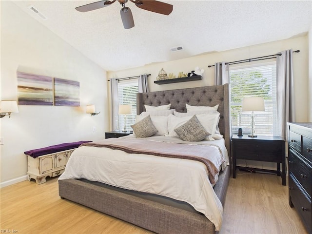 bedroom with wood finished floors, lofted ceiling, a textured ceiling, ceiling fan, and baseboards