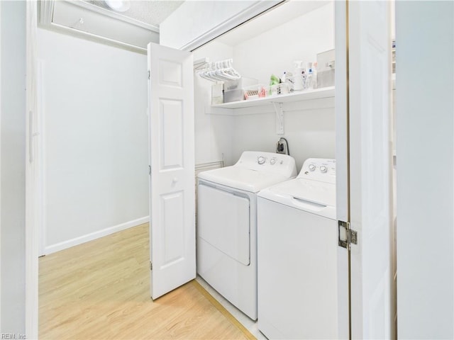 laundry area with washing machine and dryer, light wood-style flooring, and baseboards
