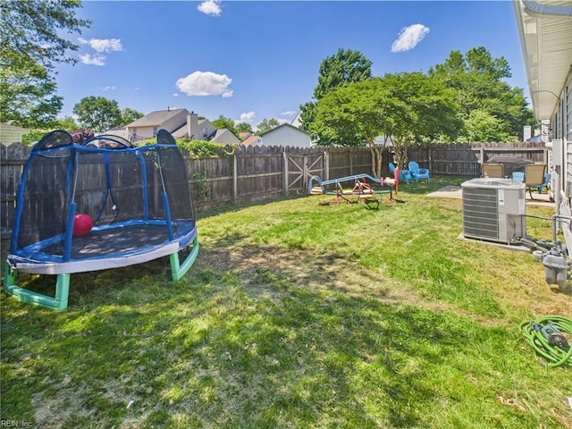 view of yard featuring a trampoline and central air condition unit