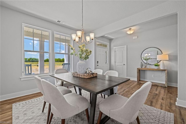 dining room with a chandelier, baseboards, and wood finished floors