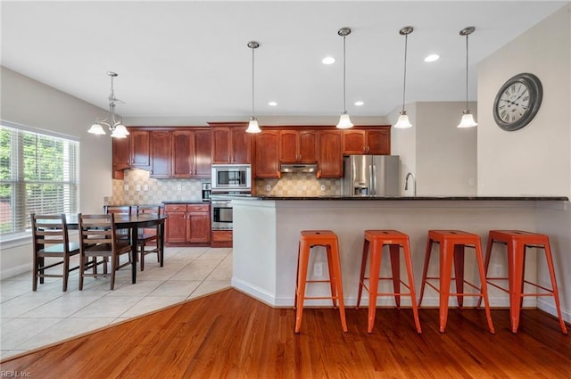 816 Dawson Cir, Chesapeake, VA 23322 - kitchen with appliances with stainless steel finishes, under cabinet range hood, a kitchen bar, decorative backsplash, and recessed lighting