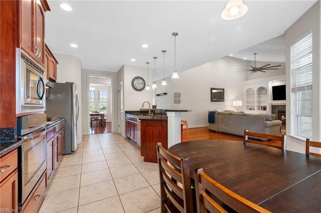 816 Dawson Cir, Chesapeake, VA 23322 - kitchen with stainless steel appliances, a ceiling fan, lofted ceiling, a lit fireplace, and decorative light fixtures