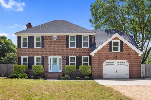 colonial home with a chimney, a garage, driveway, and brick siding