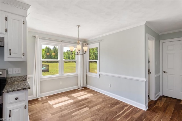 unfurnished dining area with a chandelier, light wood-style flooring, baseboards, and crown molding