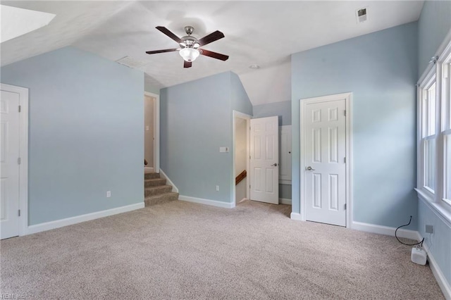 unfurnished bedroom featuring vaulted ceiling, carpet floors, baseboards, and a ceiling fan