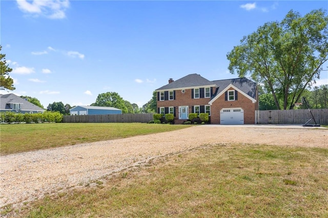 colonial-style house featuring driveway, brick siding, and a chimney