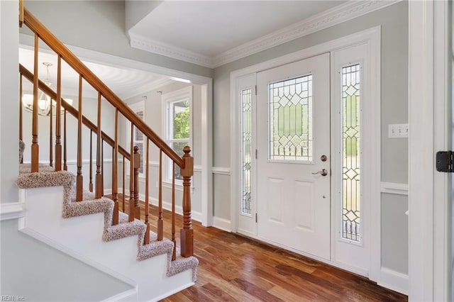 entryway with wood finished floors, stairway, and crown molding