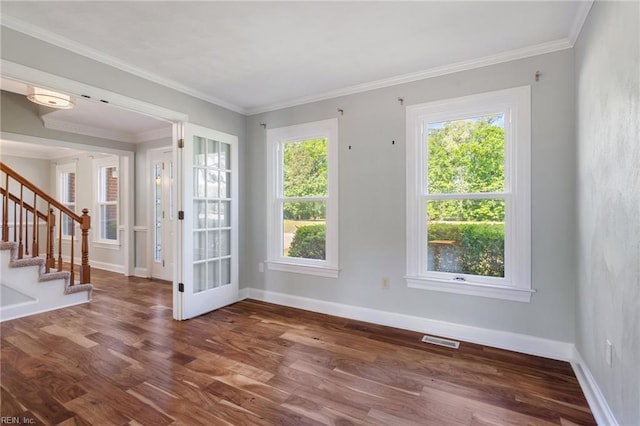 unfurnished room with plenty of natural light, wood finished floors, stairs, baseboards, and crown molding