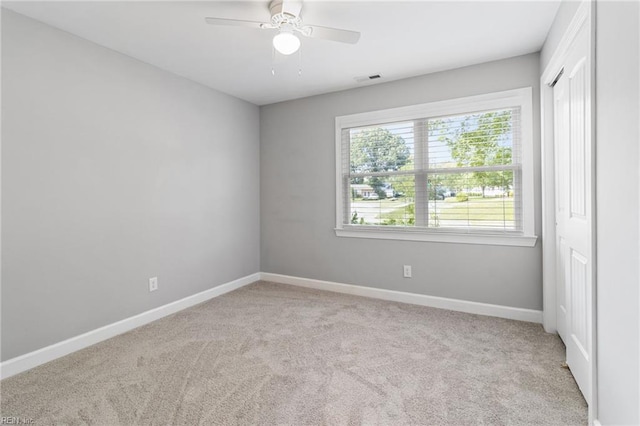 carpeted empty room featuring baseboards and ceiling fan