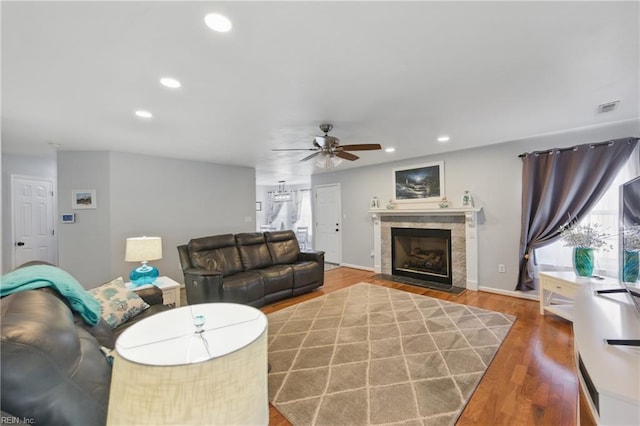 living room featuring ceiling fan, wood finished floors, a fireplace with flush hearth, recessed lighting, and baseboards