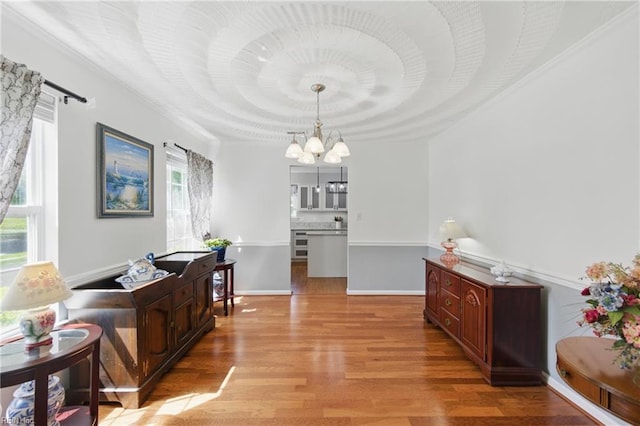dining space featuring a chandelier, light wood-type flooring, and crown molding