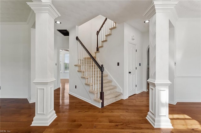 stairs with wood finished floors, decorative columns, baseboards, recessed lighting, and ornamental molding