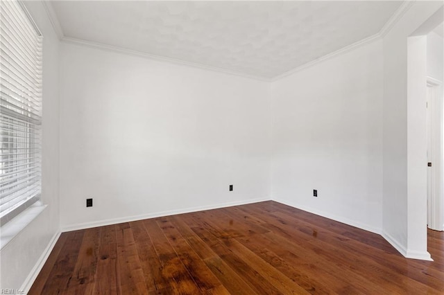 empty room with wood-type flooring, baseboards, and ornamental molding