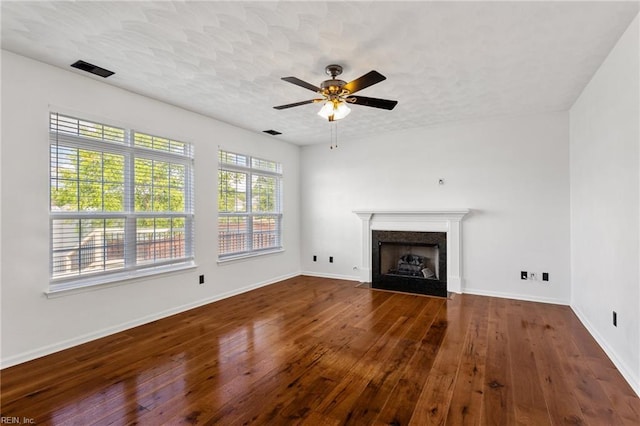 unfurnished living room with wood-type flooring, a ceiling fan, baseboards, and a premium fireplace