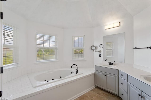 full bathroom featuring a tub with jets, double vanity, tile patterned floors, and vaulted ceiling