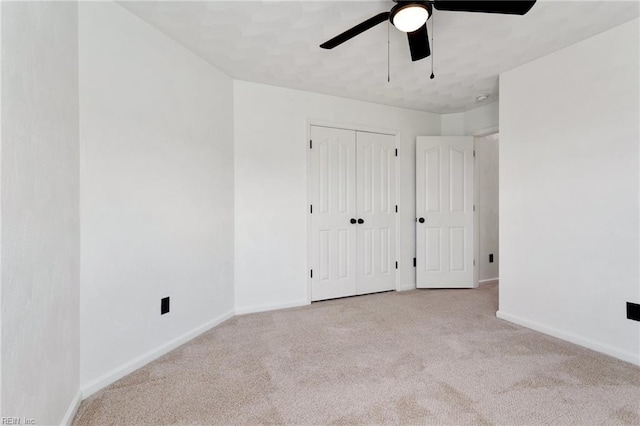 unfurnished bedroom with carpet flooring, baseboards, a closet, and a ceiling fan