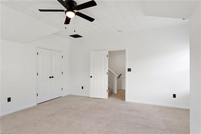 unfurnished bedroom with light carpet, baseboards, ceiling fan, and a closet