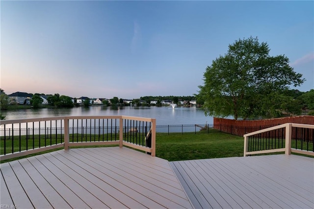 deck at dusk featuring a water view