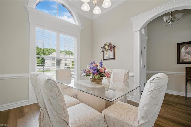 dining area with a chandelier, wood finished floors, arched walkways, healthy amount of natural light, and ornamental molding
