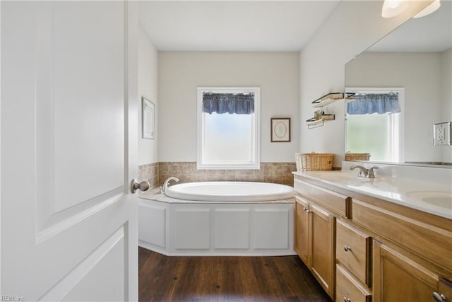 bathroom featuring double vanity, a garden tub, and wood finished floors