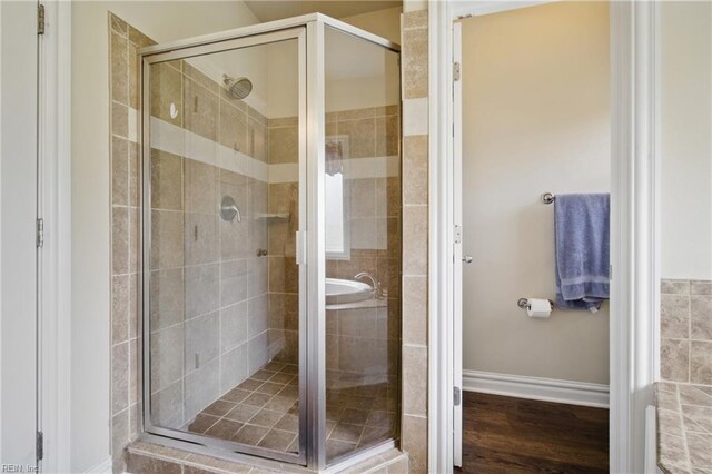 bathroom featuring a stall shower, baseboards, and wood finished floors