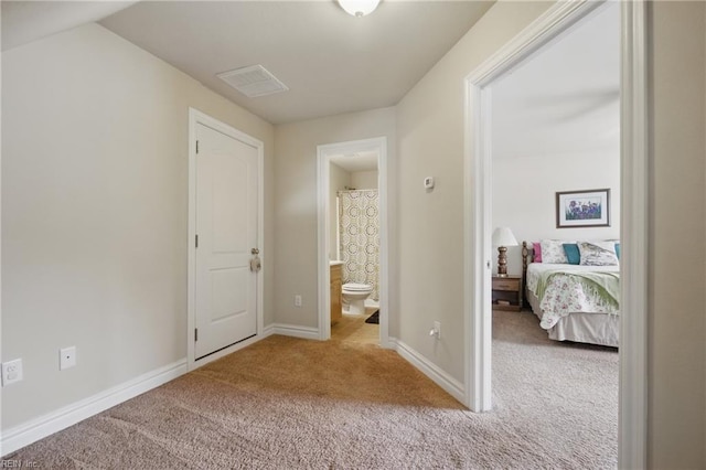 bedroom with light carpet, baseboards, and ensuite bathroom