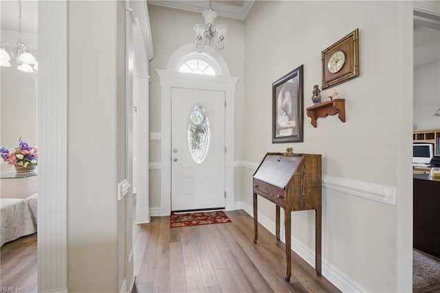 foyer entrance featuring a chandelier, wood finished floors, crown molding, and baseboards