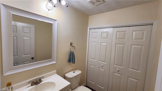bathroom with a closet, toilet, and vanity