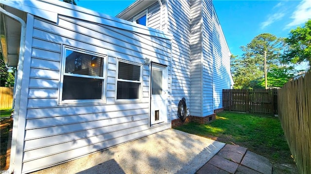 view of side of home with a fenced backyard, a chimney, and a patio area