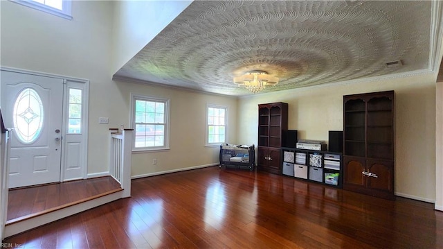 foyer featuring wood-type flooring, crown molding, and baseboards