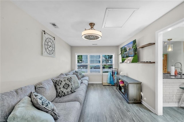 living area featuring attic access, wood finished floors, and baseboards
