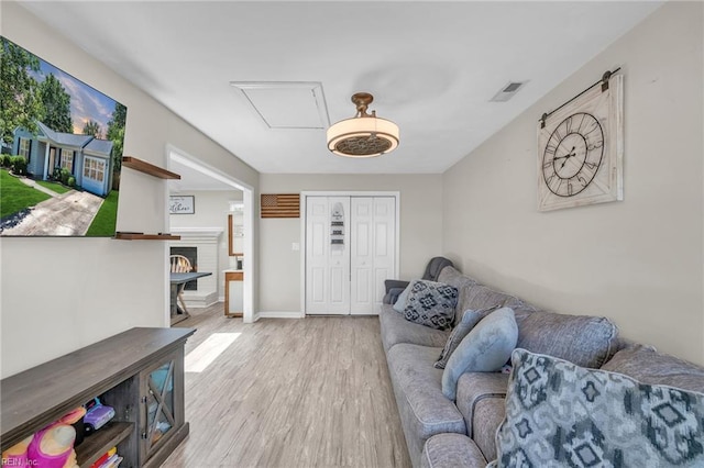 living area with light wood finished floors, a warm lit fireplace, and baseboards