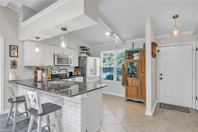 kitchen with stainless steel appliances, dark stone counters, a peninsula, ornamental molding, and a sink