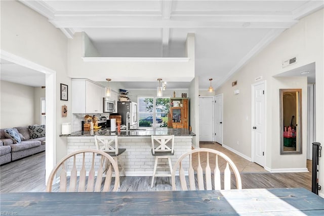 dining room with light wood-style flooring, crown molding, beamed ceiling, and baseboards