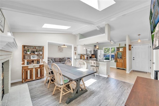 dining area with a skylight, a fireplace, crown molding, and baseboards