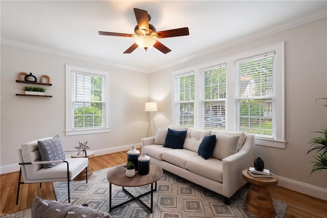 living room featuring baseboards, crown molding, ceiling fan, and wood finished floors