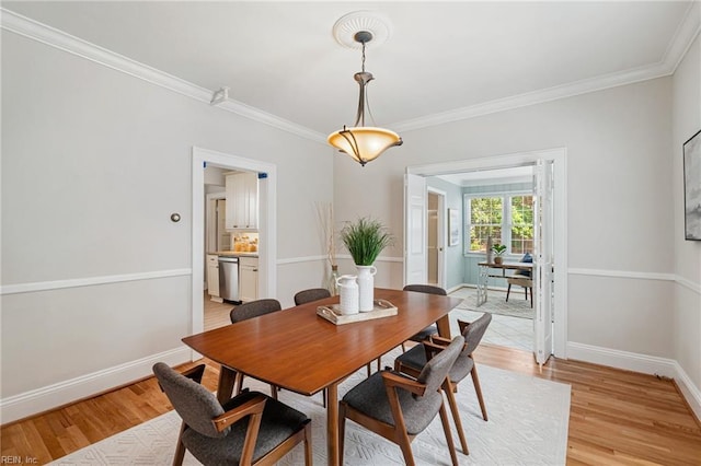 dining area with light wood-type flooring, baseboards, and crown molding