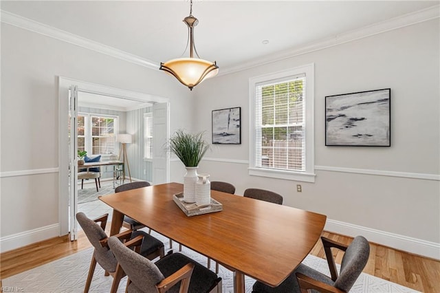 dining room featuring baseboards, light wood-style floors, and ornamental molding