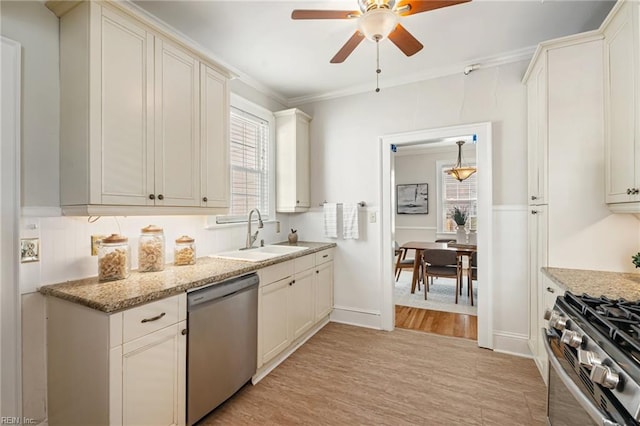 kitchen featuring stainless steel appliances, a sink, a ceiling fan, ornamental molding, and light wood-style floors